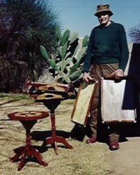 Oom Len Henning (91) met 'n paar van die tafeltjies en skinkborede wat hy die afgelope paar weke gemaak het. Deesdae kos hulle net 'n glimlag